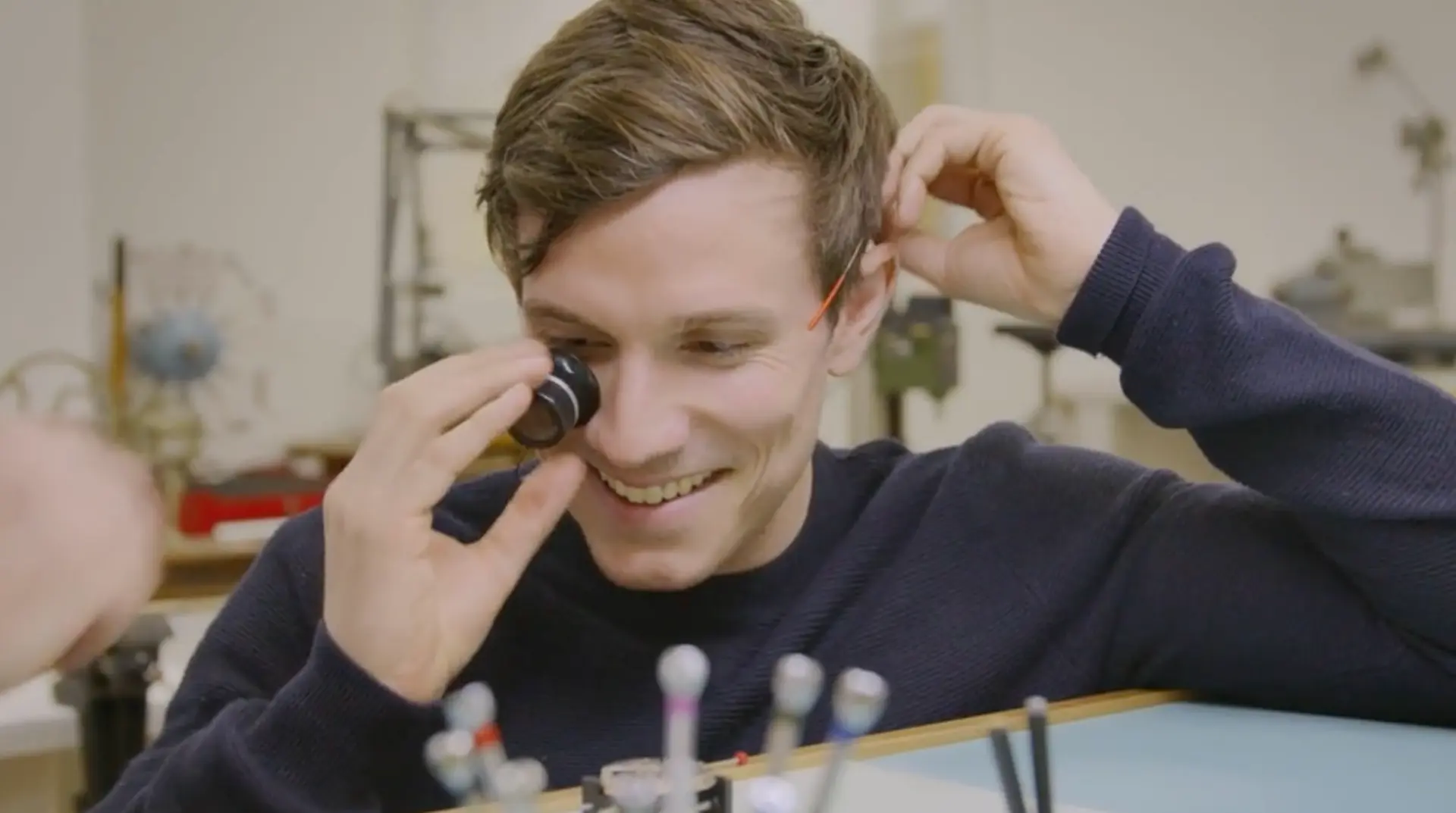 Presenter Will Best examining a camera lens during filming for Pearson Roadmap